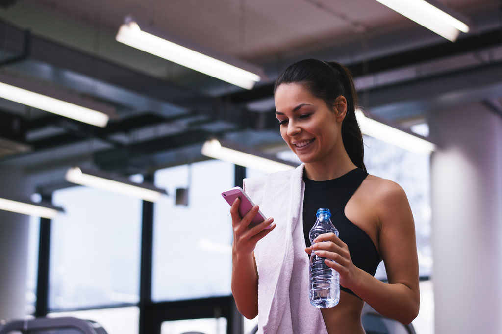 Woman logs her workouts using online personal training app